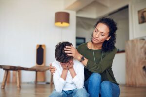 A child feeling depressed being comforted by a mother, illustrating what causes depression in children